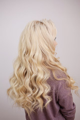 Naklejka premium Back view of blonde with long luxurious curls.