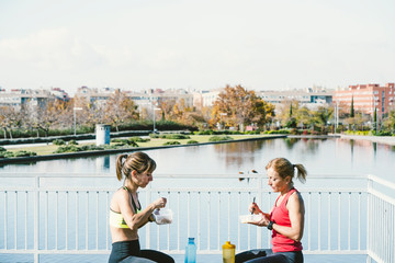 Fototapeta na wymiar Two women eating in the park after training