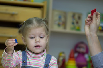 little girl playing and studying on lessons in kindergarden