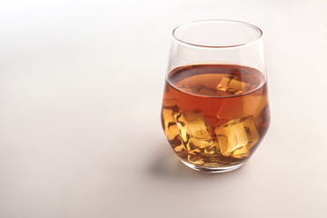 Glass of whisky with ice on white background