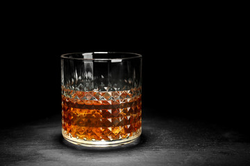 Glass of whisky on table against black background