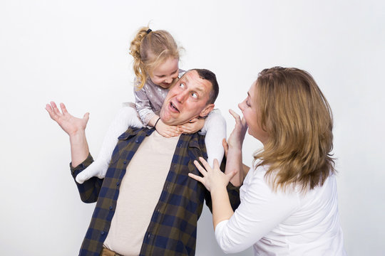 Portrait of a happy family smiling on gray background. Children daughter sit on father's shoulders, mom laughing and hugging. Family holiday and togetherness.