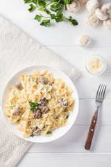 Top view pasta with mushroom and parsley on white wooden table.
