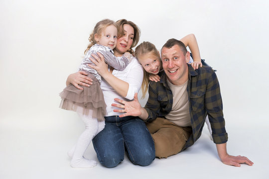 Portrait of a happy family smiling on gray background. Two children daughters, father, mom laughing and hugging. Family holiday and togetherness.