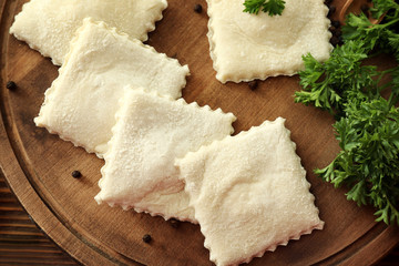 Tasty ravioli on wooden board, closeup