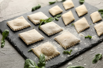 Slate plate with tasty ravioli on table, closeup