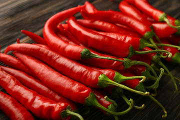 Fresh chili peppers on wooden table, closeup