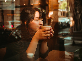 Asian woman drinking coffee in coffee shop cafe