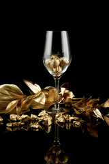 Wineglass with gold walnuts and nuggets on dark background