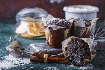 Carrot-chocolate muffin dusted with icing sugar, a cup of tea, baking ingredients. Flour, eggs,...