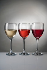 Glasses with different kinds of wine on grey background