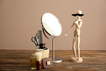 Funny small mannequin with mustache and foam in front of mirror on wooden table