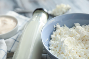 Bowl with cottage cheese and bottle of milk on table