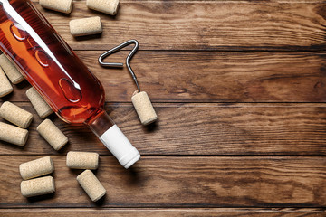 Bottle of red wine with corks on wooden background