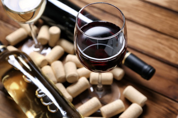 Glass of red wine with corks on wooden table