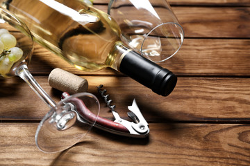 Bottle of white wine with glasses and corkscrew on wooden table