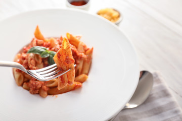 Fork with tasty penne pasta, closeup