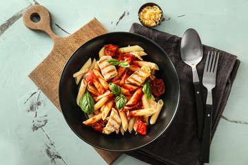 Plate with tasty penne pasta and tomato sauce on light table