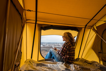 Free alternative vacation woman inside a tent looking at the panorama outside and use technology...