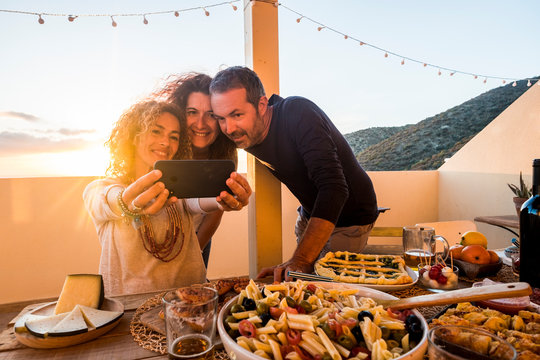 Group of people friednship concept have fun together taking selfie during a dinner or lunch outdoor at home in the terrace - firends and caucasian women and man eat and drink to celebrate