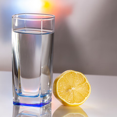 A glass of lemonade on a light background with splashing water