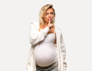 Pregnant blonde woman with white sweatshirt showing a sign of closing mouth and silence gesture on...