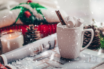 Christmas decor: Warm sweater, cup of hot cocoa with marshmallow, candy, candles and Christmas tree. Winter mood, decoration.