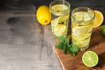 Glasses of water with lemon on grey table