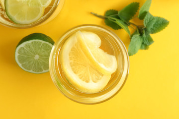 Glasses of water with lemon and lime on color table