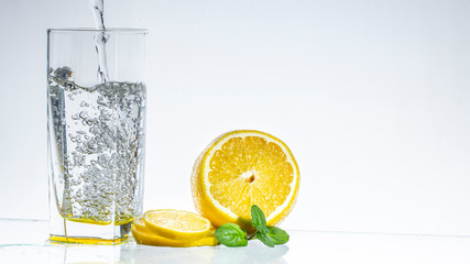 A glass of lemonade on a light background with splashing water