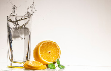 A glass of lemonade on a light background with splashing water
