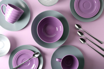 Set of clean tableware on color background