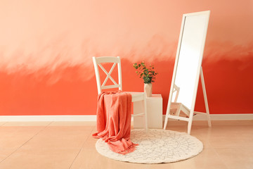 White chair with big mirror near pink wall