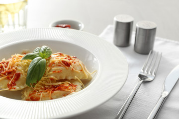 Plate with cooked ravioli on table