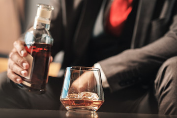 Close up of businessman wearing red tie holding bottle of cognac