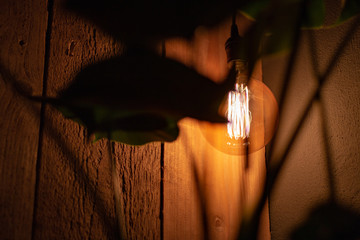 Design lamp with old-fashioned filament hanging in front of a scaffold wood wall