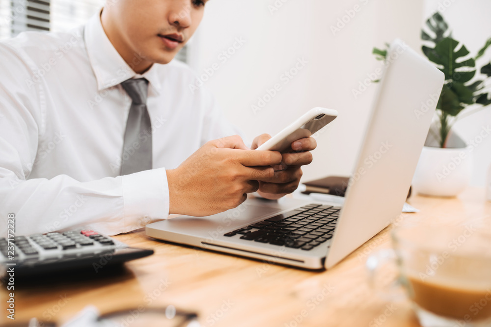 Poster business man busy working on laptop computer and using mobile smart phone in modern office, close up