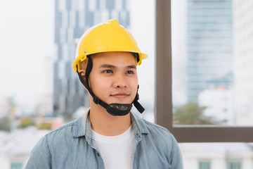Young man worker with a yellow helmet on the construction site.
