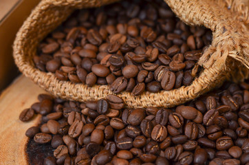 A sack of roasted coffee beans on wooden