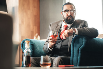 Bearded dark-haired lawyer drinking alcohol and smoking cigar