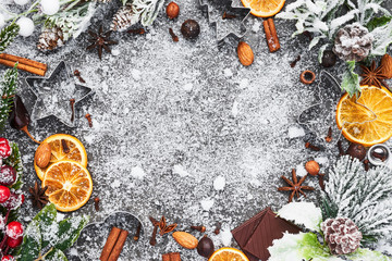 Holiday baking background for baking Christmas cookies with cutters and spices on grey concrete table with snow. Holiday baking or cooking ingredients. Christmas food. Top view with copy space.