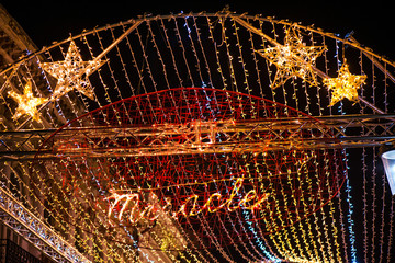Fototapeta na wymiar Blurry, abstract Christmas background. Glowing reindeer, stars and light stripes on dark, romantic night sky background. Christmas market and decorations in city center. 