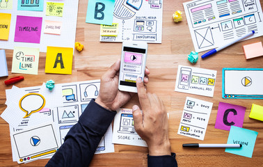 Business digital marketing with paperwork sketch and male hand touching smartphone on wood table.analysis strategy concepts