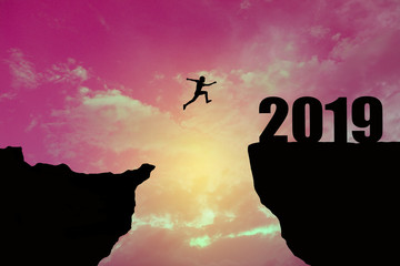 Man jumping 2019. man jumping over cliff on sunset background,Business concept idea