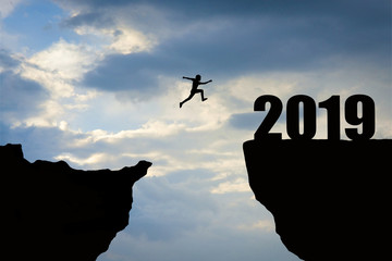 Man jumping 2019. man jumping over cliff on sunset background,Business concept idea