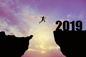 Man jumping 2019. man jumping over cliff on sunset background,Business concept idea