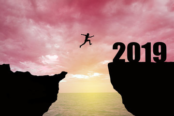 Man jumping 2019. man jumping over cliff on sunset background,Business concept idea