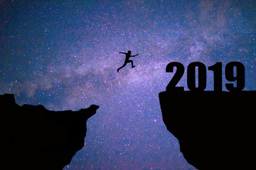 Man jumping 2019. man jumping over cliff on sunset background,Business concept idea