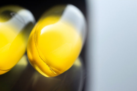 Omega 3 supplement, fish oil yellow capsules on dark background, macro image