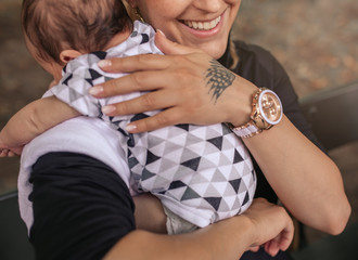 Smiling mother sitting outside holding her cute baby boy